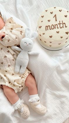 a baby sleeping next to a 1 month cake