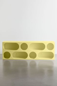 a yellow shelf sitting on top of a floor next to a white wall with circles