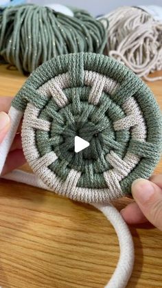 a person is holding a piece of yarn in front of some balls of yarn on a table