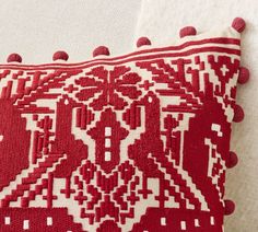 a red and white pillow with pom - poms on the bottom of it