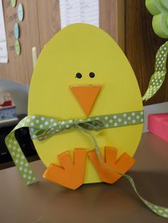 a yellow chick with green polka dots on it's head and legs is holding a ribbon