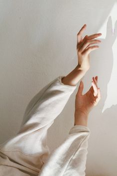 a person reaching up to touch the wall with their hand and shadow on the wall