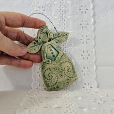 a hand holding an ornament that is on a lace tablecloth