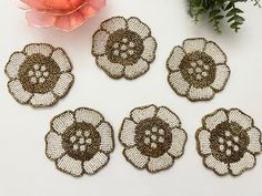 four pieces of brown and white doily with flowers on them next to a pink flower