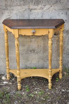 an old yellow table sitting in front of a cement wall