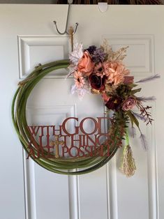 a wreath hanging on the front door with flowers and words that read, go with god nothing is possible