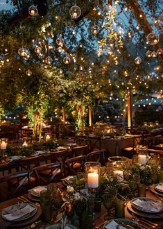 an outdoor dining area is lit up at night with candles and greenery on the tables