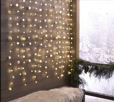 a bed sitting next to a window covered in christmas lights on the side of a wall