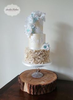 a three tiered wedding cake sitting on top of a wooden table next to a slice of tree trunk