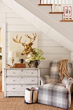 a living room with a chair, dresser and deer head on the wall