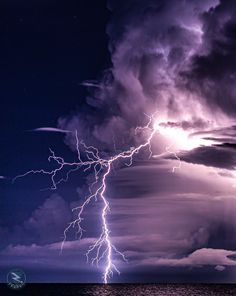 lightning striking over the ocean on a cloudy night