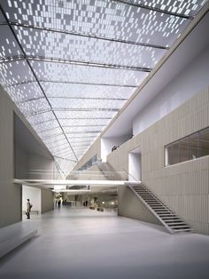 the interior of an empty building with people walking around and stairs leading up to it