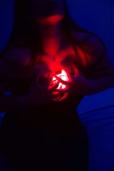 a woman holding a lit up object in her hands with blue light shining on her chest