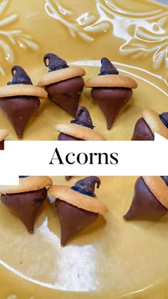 several pieces of chocolate covered pastries on a yellow plate with the word acorns above them