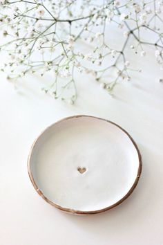 a white vase with flowers in it sitting on a table