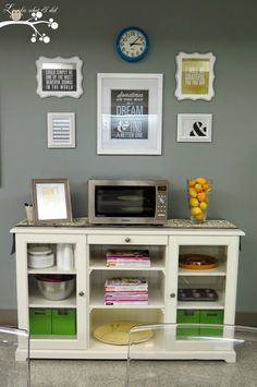 a white entertainment center with green bins and pictures on the wall next to it