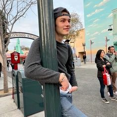 a man leaning against a pole on the street