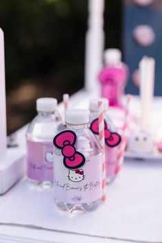 hello kitty water bottles are lined up on a table with candy sticks and other items