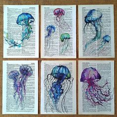 four different colored jellyfishs sitting on top of an old book page with watercolor ink