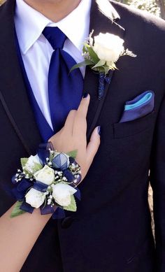 a close up of a person wearing a suit and tie with flowers on his lapel