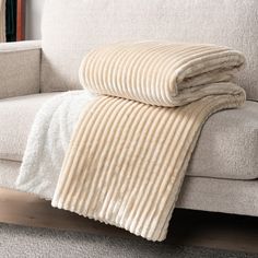 a beige blanket sitting on top of a couch