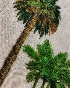 two embroidered palm trees on white fabric