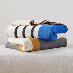 three towels stacked on top of each other in different colors and patterns, with one folded up to the side