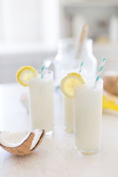 two glasses filled with lemonade sitting on top of a table next to each other