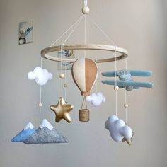 a baby mobile with clouds, hot air balloons and stars hanging from it's sides