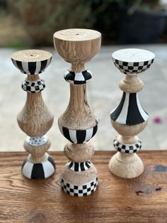 three wooden candlesticks with black and white checkered designs on them sitting on a table