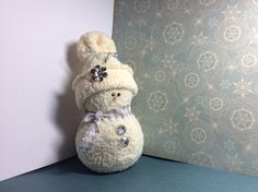 a white stuffed snowman sitting on top of a blue table next to a wall