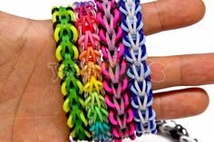 a hand is holding several different colored bracelets