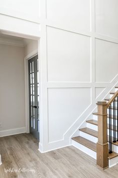 an empty room with white walls and wooden stairs