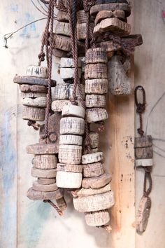 several pieces of driftwood hanging from a rope on a wooden wall with other items attached to it