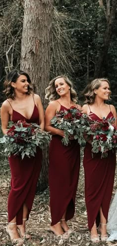 three bridesmaids in maroon dresses holding flowers and greenery