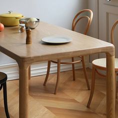 a wooden table with two chairs next to it and fruit on the plate at the end