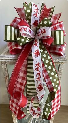 a red and green christmas bow on top of a white box with polka dot ribbon