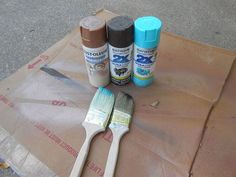 three paint brushes sitting on top of a piece of cardboard next to some other items