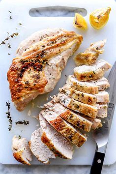 sliced chicken on a cutting board with lemons and seasoning next to the meat