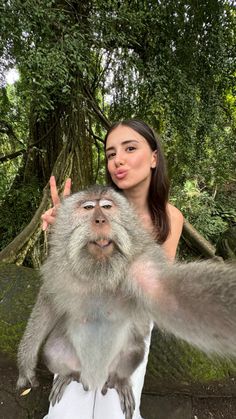 a woman standing next to a monkey with its hands in the air