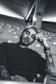 a man with tattoos sitting in a stadium