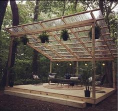 an outdoor patio with a pergolated roof and seating area surrounded by trees in the background