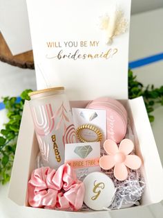 the bridesmaid gift box is filled with pink and gold accessories, including a card