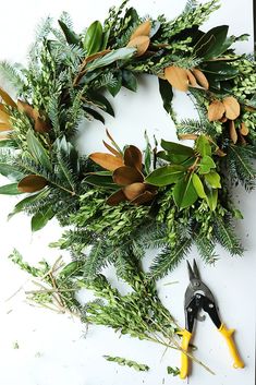 the wreath is being made with scissors and greenery