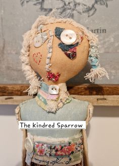 an old fashioned doll with buttons on it's head and hair is sitting in front of a painting