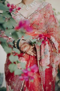 a woman in a red sari with flowers on her chest and arms around her waist