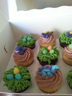 cupcakes decorated with green and blue icing in a box