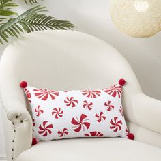 a red and white pillow sitting on top of a chair next to a potted plant