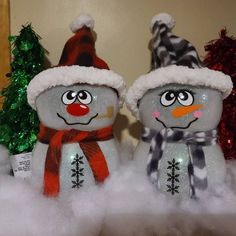 two snowmen with hats and scarfs are in the snow