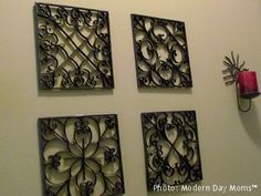 four square metal wall art pieces hanging on the wall next to a red candle holder